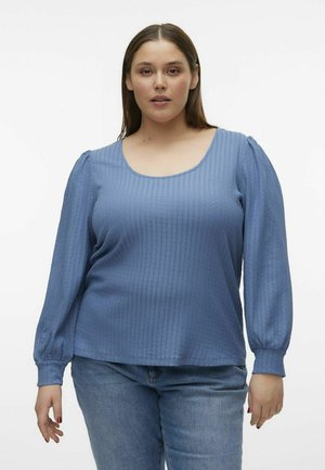 Lyseblå langærmet bluse med en rund halsudskæring, tekstureret ribbet mønster og puffede ærmer, parret med mellemvaske blåjeans.