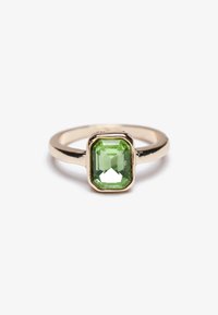 Bague dorée mettant en valeur une pierre précieuse verte rectangulaire et facettée, sertie dans un élégant cadre à griffes avec un anneau poli.