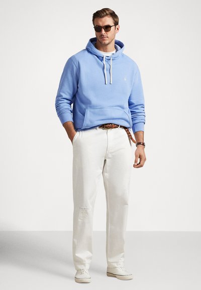 Šviesiai mėlynas džemperis su užtraukiamomis virvelėmis, priekine kišene, derinamas su baltais nusidėvėjusiais kelnėmis ir baltais sportbačiais. Papuošta akiniais nuo saulės ir diržu.