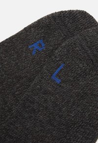 Chaussettes en tricot gris charbon avec des lettres brodées bleues "R" et "L" pour droite et gauche. Texture douce, épaisseur moyenne.