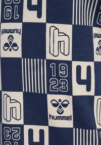 Blå och vit mönstrad textil med geometriska former, siffror och "hummel"-logotypen, med varierande texturer och designer.