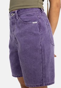 Lila jeansshorts med avslappnad passform, dekorerade med stickningar, knappstängning och en logotypetikett på bakfickan.