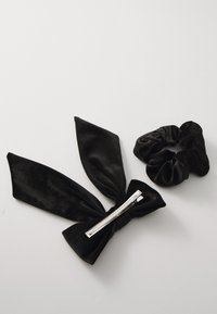 Black hair accessories include a velvet bow with zipper detail and a matching scrunchie, both featuring a smooth texture.