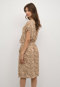 Rochie bej cu model zebrat, maneci scurte, talie elastică, lungime până la genunchi, material ușor, design drapat și buzunare laterale.