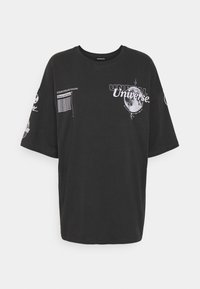 Zwarte oversized t-shirt van katoen. Bevat grafische prints, waaronder "UNREAL Universe" en verschillende textelementen op de mouwen.