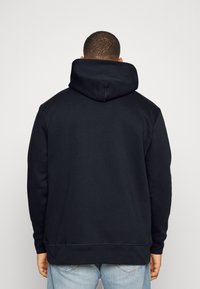 Felpa con cappuccio di un navy scuro realizzata in cotone misto. Presenta una tasca a marsupio, polsini a coste e una vestibilità rilassata con un design classico.