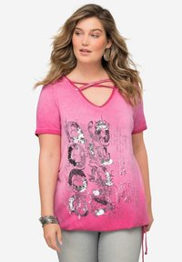 Vaaleanpunainen puuvillateeppari, jossa on V-pääntie, ristiselkäyksityiskohta, lyhyet hihat ja paljettiprintti. Mukana on kiristettävä helma.