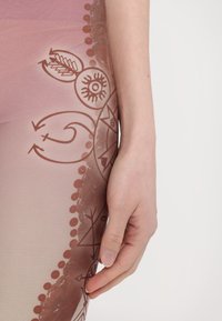 Leggings featuring a gradient pink pattern with brown geometric shapes and symbols. Smooth texture with decorative accents.