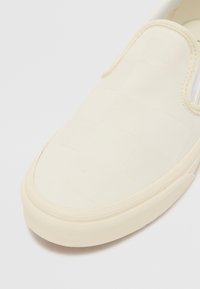 Pantofii slip-on din textil of-white cu un model texturat țesut, talpă din cauciuc și accente elastice pe laturile pentru o purtare ușoară.