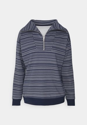 Sudadera de forro polar azul marino con cuello de media cremallera, que presenta un diseño con líneas y formas geométricas blancas, mangas largas y puños acanalados.