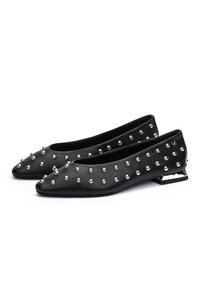 Ballerines noires à bout pointu décorées de clous argentés répartis de manière uniforme et à talons blocs bas avec un design découpé géométrique.