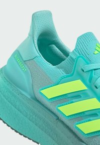 Turquoise Adidas Ultraboost sneaker featuring breathable mesh upper, padded collar, neon green stripes, and textured rubber sole.