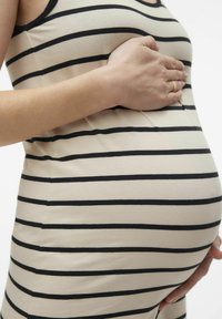 Mammaklänning i beige med svarta horisontella ränder, som sitter tajt runt en rundad buk. Slät tyg, figurnära design och ärmlös skärning.