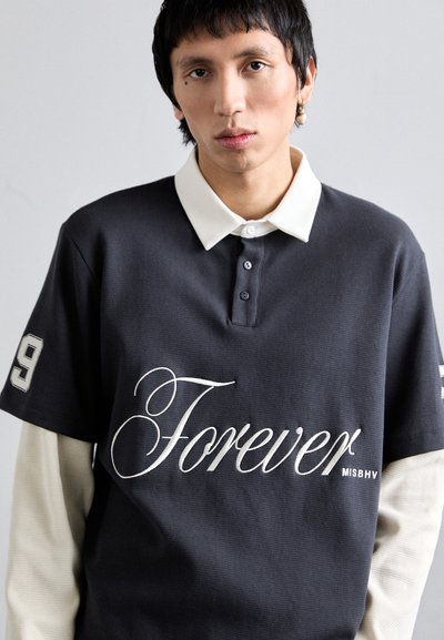 Polo de manga corta, gris oscuro, con un color blanco. Presenta "Forever" en cursiva y un "9" en la manga. Tejido texturizado, corte relajado.