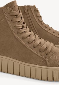 Beige Wildleder High-Top-Sneaker mit strukturierter Oberfläche, runder Zehenpartie und dicker, geriffelter Gummisohle. Mit Schnürsenkeln und einem Reißverschluss an der Seite.