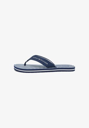 Marineblaue und weiße gestreifte Flip-Flops mit marineblauem Stoffriemen, auf dem der Schriftzug „Tommy Hilfiger“ und das Logo zu sehen sind; flache Sohle auf weißem Hintergrund.