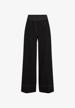 Pantalons larges noirs avec une ceinture élastique texturée. Caractéristiques de coutures blanches le long des poches et des ourlets. Fini en tissu lisse.
