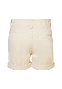 Shorts en coton crème avec un ourlet replié, une taille élastique et une poche arrière unique. Texture lisse et coupe ajustée.