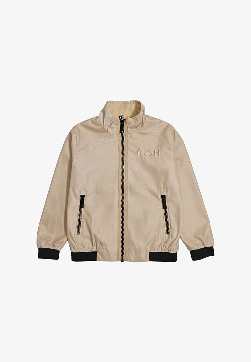 Giacca bomber beige con cerniera nera, due tasche frontali con zip, polsini e orlo neri, e la scritta "RICH" ricamata sul petto a sinistra.