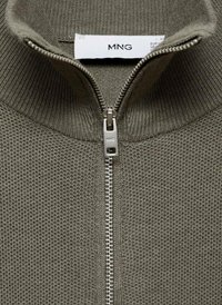 Maglione verde scuro con zip in tessuto a maglia testurizzata, caratterizzato da un colletto alto e una cerniera metallica con tirazip personalizzato. Etichetta visibile all'interno del collo.