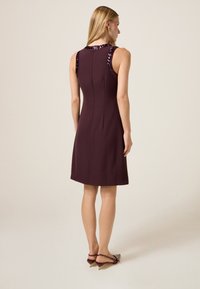 Bordowa sukienka bez rękawów z cekinowymi akcentami na ramionach, gładka tkanina, dopasowany krój i długość do kolan.