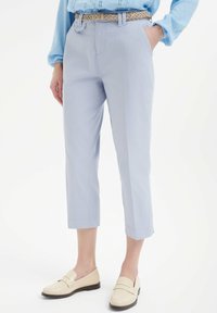 Jasnoniebieskie krótki spodnie o gładkiej teksturze, z przednimi kieszeniami i paskiem. W połączeniu z kremowymi mokasynami dla neutralnego akcentu.