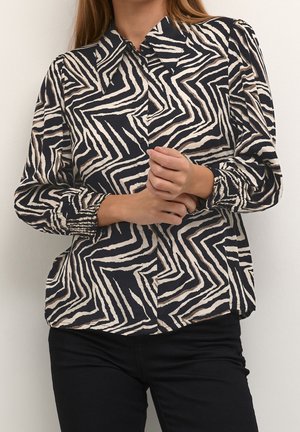 Langärmlige Bluse mit einem schwarz-cremefarbenen Zickzackmuster, Knopfverschluss vorne und gerafften Manschetten. Hergestellt aus leichtem Material.