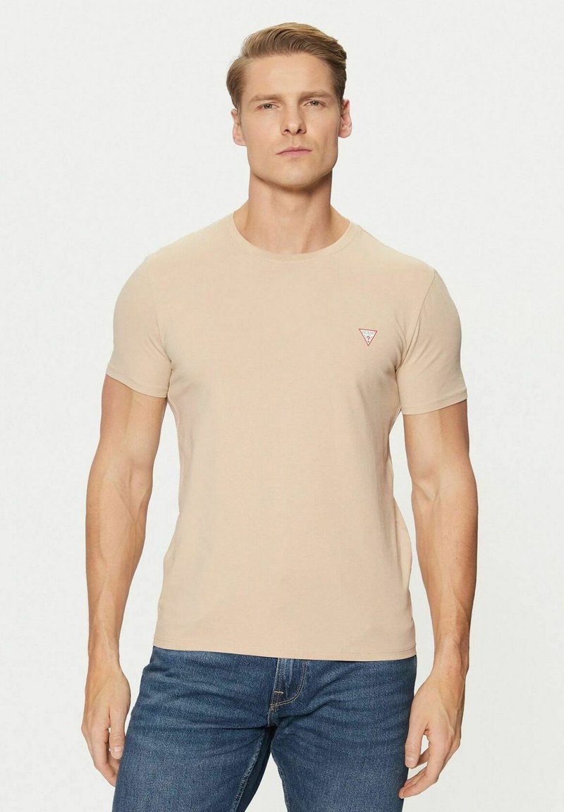 T-shirt beige a maniche corte con collo rotondo e piccolo logo a triangolo rosso sul petto. Realizzata in cotone morbido, stile slim fit.