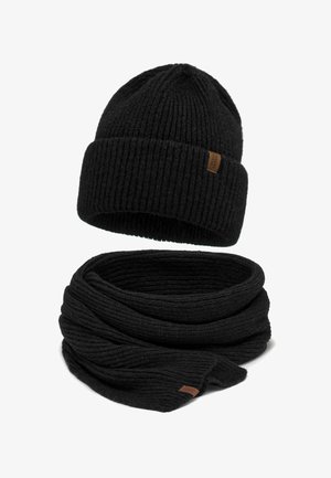 Berretto in maglia nera con risvolto e sciarpa in maglia nera abbinata, entrambi con piccoli cartellini del marchio marroni.