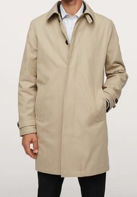 Trench-coat beige à coupe décontractée, avec une fermeture boutonnée devant, des poches latérales et des poignets à boutons. Texture de tissu lisse.