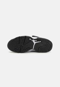 Svart gummisåle til sneaker med teksturert mønster, med en hvit Jumpman-logo og flerdireksjonelt grepdesign.