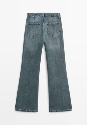 Denimjeans med vidde, i falmet blå med en blød tekstur, fem lommer og sømdetaljer langs linningen og kanten.