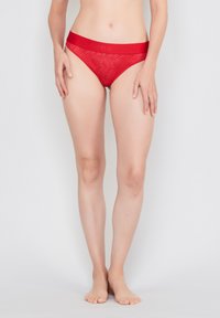 Red, sheer lace bikini underwear with a textured wave pattern, featuring a smooth, wide red waistband with subtle branding on the front.