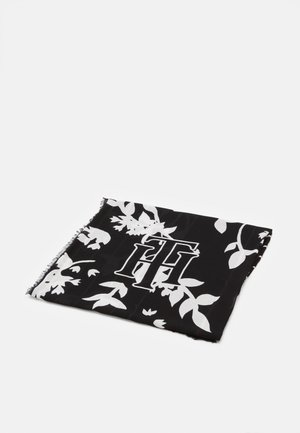 Czarny szal z białymi kwiatowymi wzorami i dużymi splecionymi inicjałami "TH", starannie złożony na jednolitym białym tle.