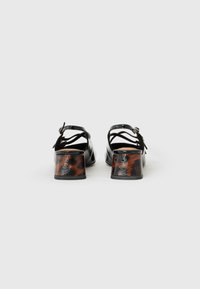 Schwarze Sandalen mit Riemchen und einem strukturierten braunen Tiermotiv-Blockabsatz. Verfügt über einen verstellbaren Knöchelriemen und ein glattes oberlederähnliches Obermaterial.