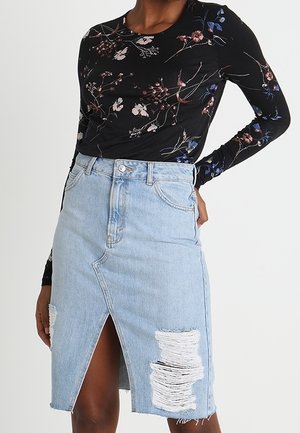 Czarna kwiecista bluzka z długim rękawem w połączeniu z jasnoniebieską spódnicą dżinsową z rozcięciem z przodu i postrzępionymi detalami. Oba elementy są dopasowane.