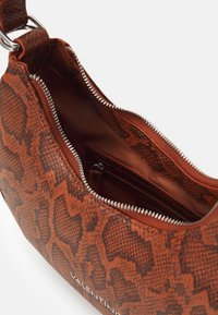 Ruskea käärmeennahkakuvioinen käsilaukku, jossa on teksturoitu pinta, hopeinen vetoketju ja sisätasku. Edessä on "Valentino"-logo.