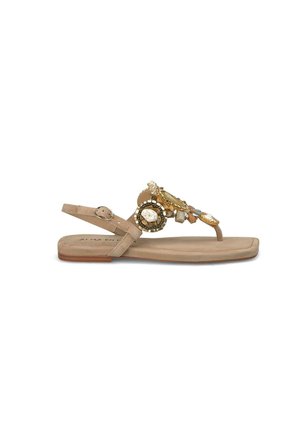 Sandalo piatto beige con cinturino alla caviglia regolabile, caratterizzato da gioielli decorativi e perline sulla parte superiore. Sottopiede morbido, design minimalista.