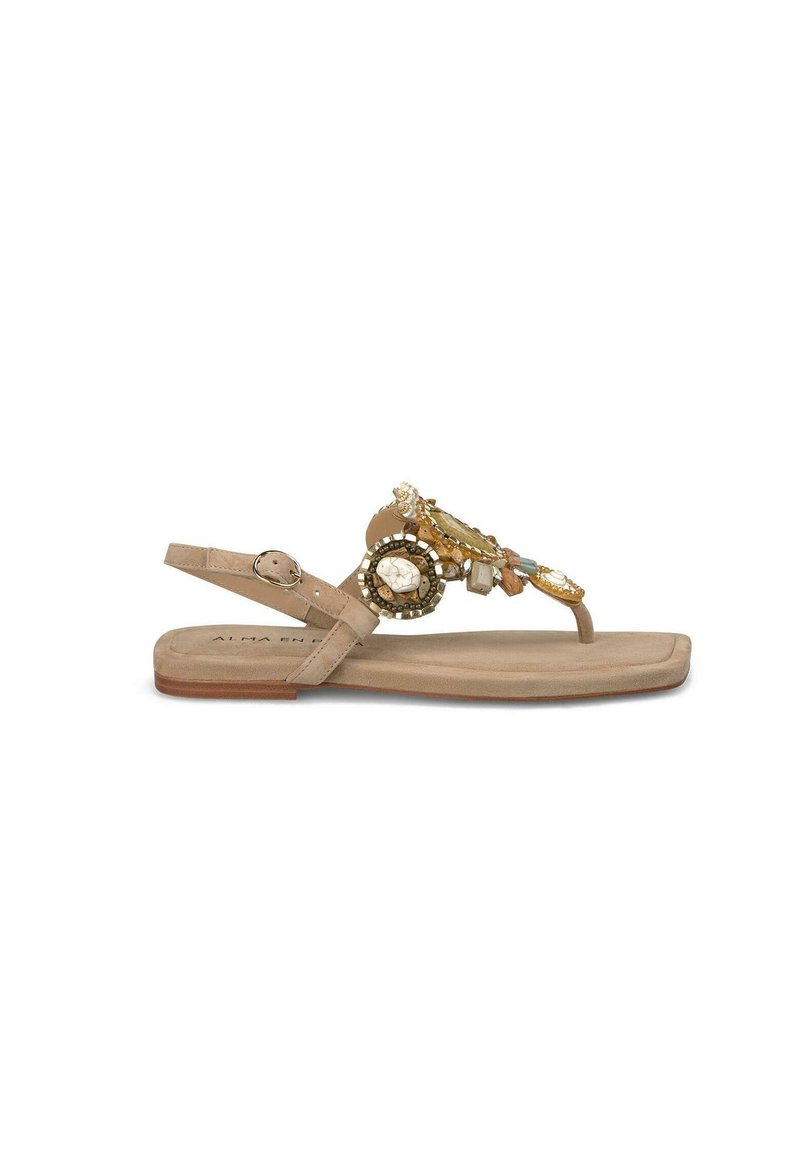 Beige platte sandaal met verstelbare enkelband, versierd met decoratieve juwelen en kralen op de bovenkant. Zacht gevoerde zool, minimalistisch ontwerp.