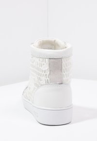 Zapatillas altas blancas con parte superior de malla texturizada, acentos de cuero suave y un detalle plateado en el talón.