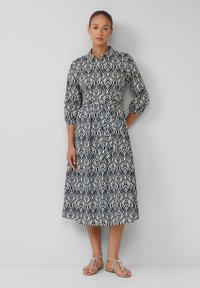 Kleid mit Navy- und Creme-Muster, das einen Kragen, drei Viertelärmel, einen Taillengürtel und einen knielangen Rock mit Blattdesign hat.