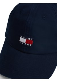 Căciulă albastră marină cu vizor curbat și curea ajustabilă; prezintă logo-ul brodat "TOMMY JEANS" în roșu, alb și albastru pe față.