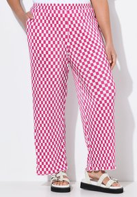 Pantaloni a gamba larga a quadretti rosa e bianchi con vita elasticizzata, dotati di tasche laterali e orlo frangiato. Abbinati a sandali bianchi.