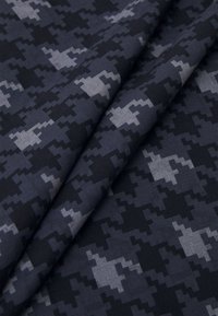 Tela con un patrón de camuflaje pixelado en tonos azul marino oscuro y gris. Textura suave con bordes doblados, que muestra un diseño moderno.