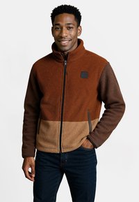 Fleecejack met een hoge kraag, ritssluiting en een kleurblokontwerp in bruin- en tan-tinten, voorzien van zijzakken.