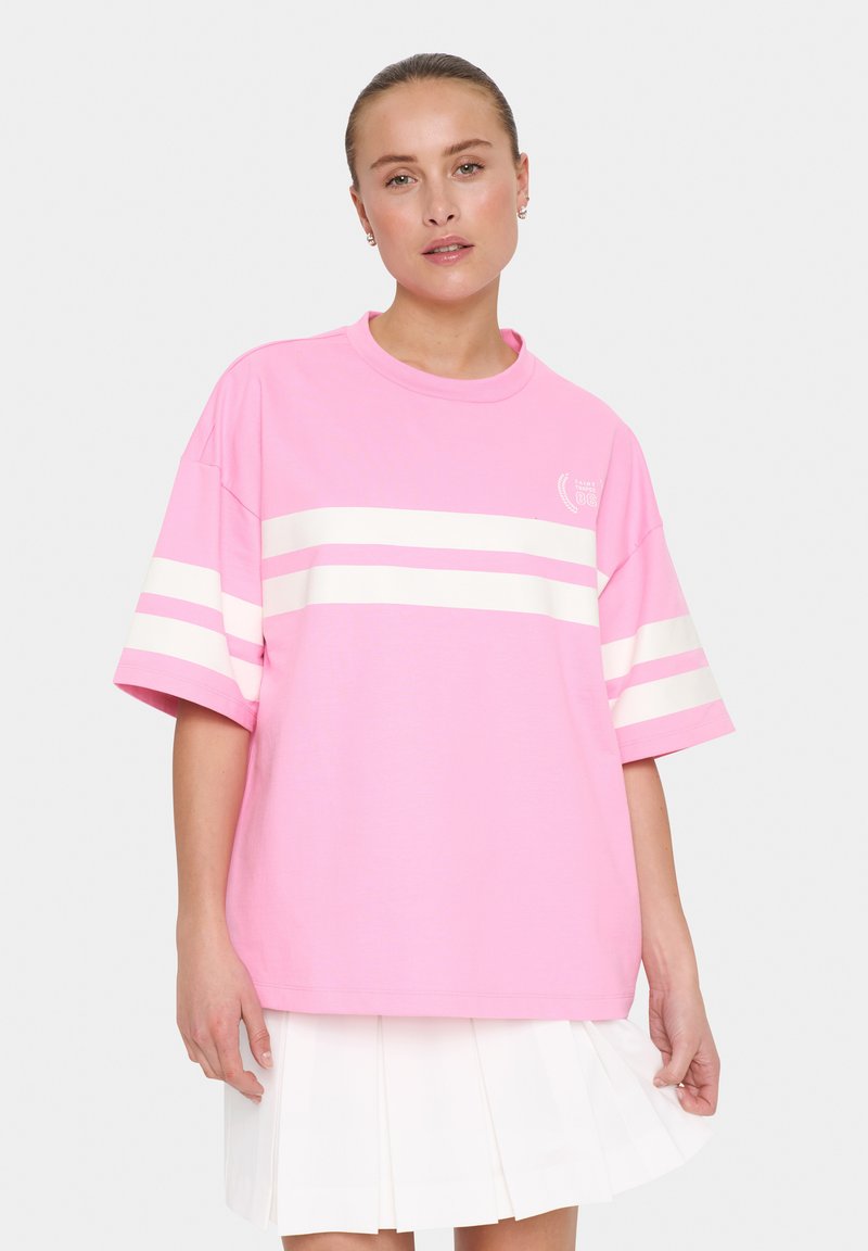 T-shirt overdimensionato rosa con righe orizzontali bianche, maniche corte e scollatura tonda. Presenta una piccola grafica sul petto.
