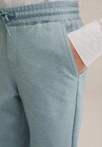 Heledad sinine dressipükstega, millel on tekstuuriga kangas, elastne vöökoht, reguleeritav nöör ja küljetasku. Sile puuvillasegu materjal.