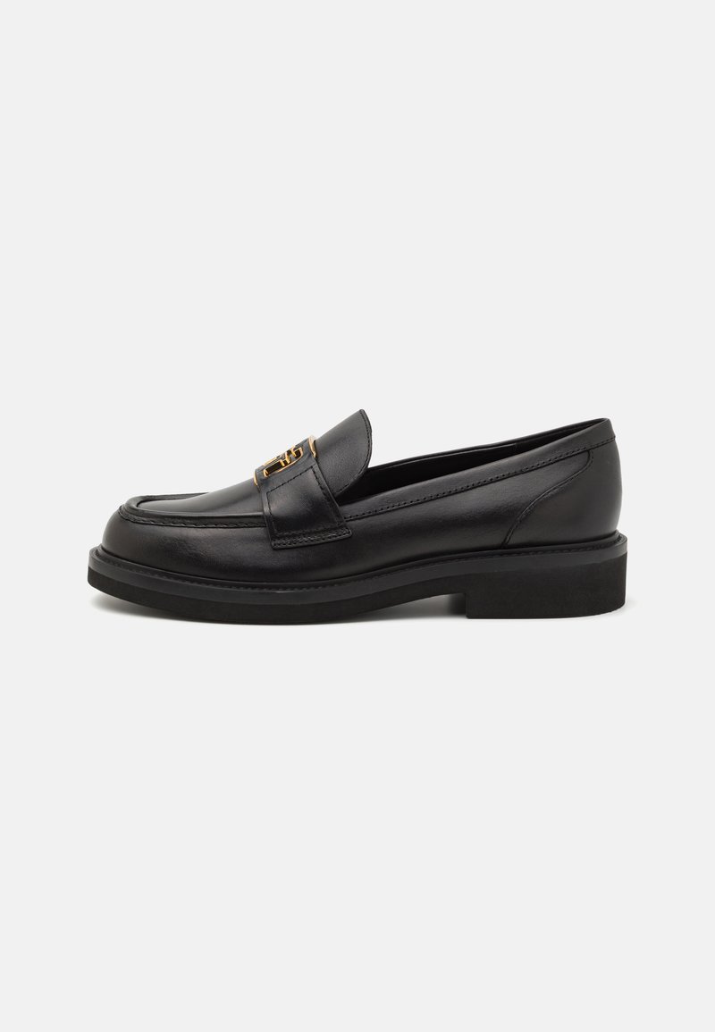 Zwarte leren loafers met een ronde neus, gestikte details, gouden hardware en een lage, textuur rubberen zool. Glad, strak afwerking.