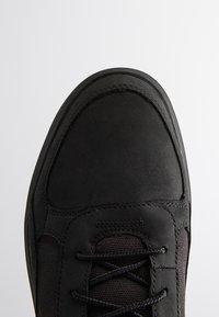 Czarne sneakersy, z gładkim skórzanym noskiem, teksturowanymi bocznymi panelami i sznurowanym zapięciem. Styczne akcenty dodają szczegółu do projektu.