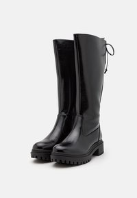 Stivali neri al ginocchio realizzati in pelle lucida con un design elegante, punta arrotondata, suola spessa e testurizzata, e dettaglio in pizzo regolabile sulla parte superiore.